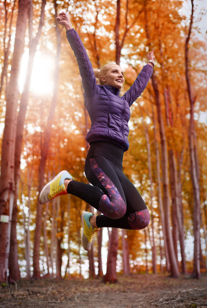Sportieve vrouw springen in herfst bos  - Foto, afbeelding