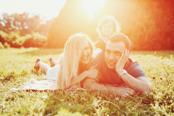 幸せな若い家族は緑の自然の中で一緒に時間を過ごす. - 写真・画像