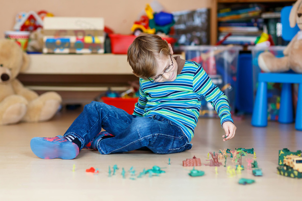 Хлопчик грає з іграшковими солдатами в приміщенні в дитячій кімнаті
 - Фото, зображення