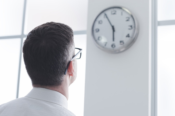 Businessman staring at the clock - Zdjęcie, obraz