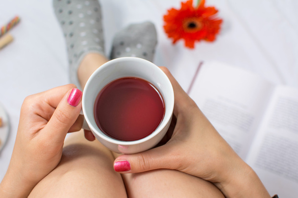 Femme tenant une tasse de thé au lit
 - Photo, image