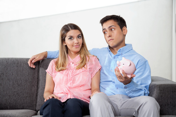 Man Holding Piggybank While Sitting With Woman - Foto, immagini