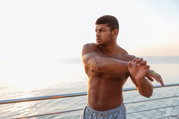 Athletic african sportsman standing and stretching arms on pier - Foto, Bild