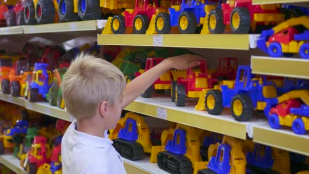 een kind in een speelgoedwinkel kijken naar een auto - Video
