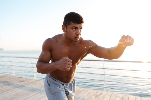 Young afro american sportsman doing boxing exercises at the pier - Fotoğraf, Görsel