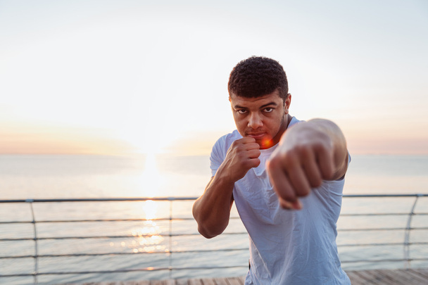 Handsome african man boxer practicing shadow boxing on sunrise - Foto, Imagen
