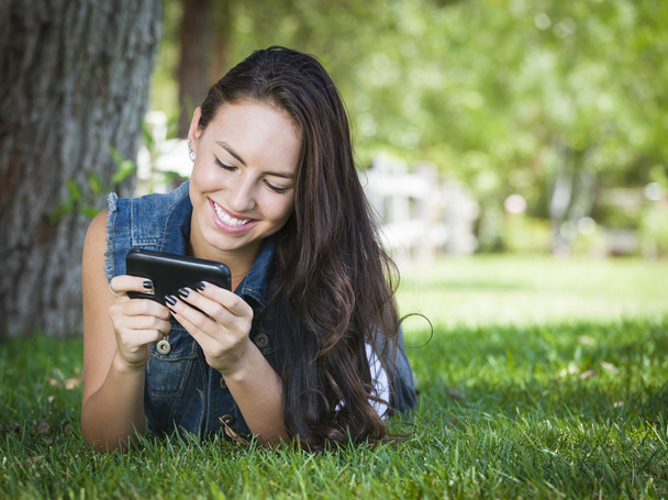 Junge Frau mit gemischter Rasse textet draußen auf Handy - Foto, Bild