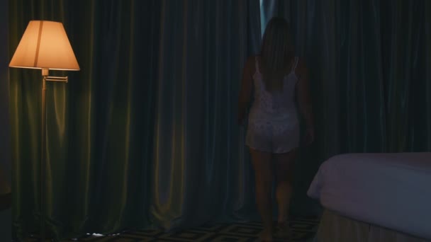 Blond žena roztáhnout závěsy v ložnici - Záběry, video