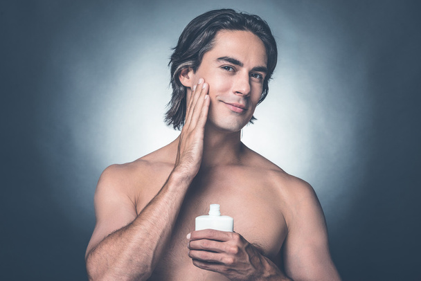 shirtless man  applying aftershave lotion - Foto, afbeelding