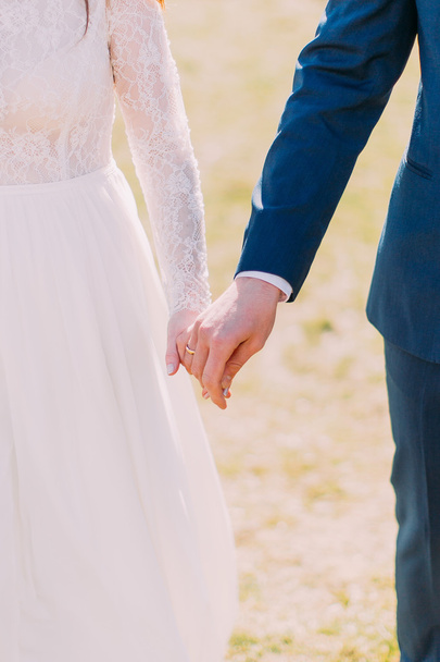 Closeup view of married bride and groom holding hands together - Photo, Image