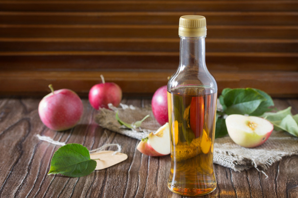 Яблучний оцет у скляній пляшці зі свіжими яблуками на табуреті
 - Фото, зображення
