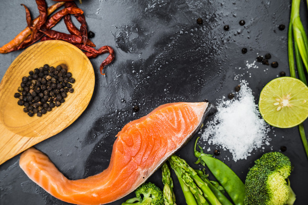 Fresh raw salmon filet with spicy herbs on black plate - Foto, afbeelding