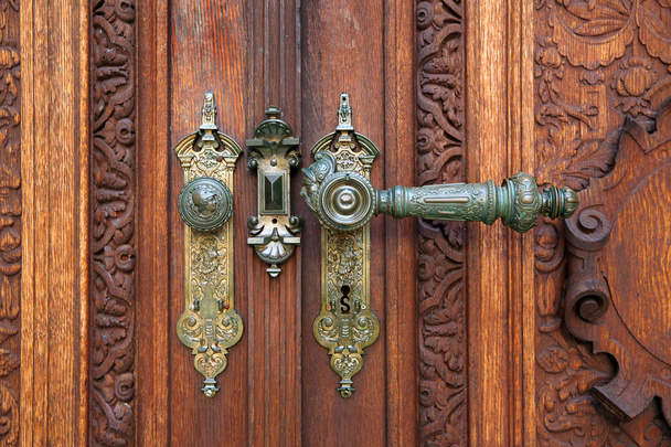  vieux stylo en métal ajouré en fer forgé avec un puits pour la clé sur la vieille porte en bois d'un vieux château avec un ornement sculpté
 - Photo, image