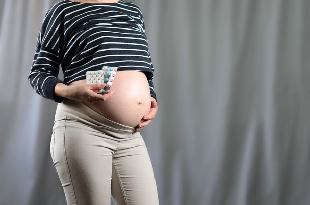 Una donna incinta con una pillola in mano. Pancia incinta. In previsione
  - Foto, immagini