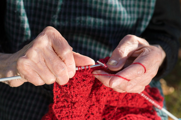 Mujeres mayores tejiendo con lana roja
 - Foto, imagen