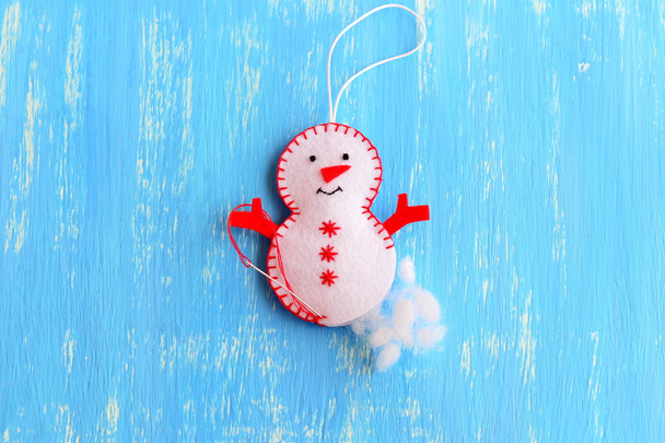 Hoe maak je een kerst voelde sneeuwpop ornament. Decoratie stap voor stap. Vul het vilt kerst sneeuwpop ornament met holle vezel. Kids kerstboom ornament decoratie naaien ambachten. Blauwe houten achtergrond. Bovenaanzicht - Foto, afbeelding