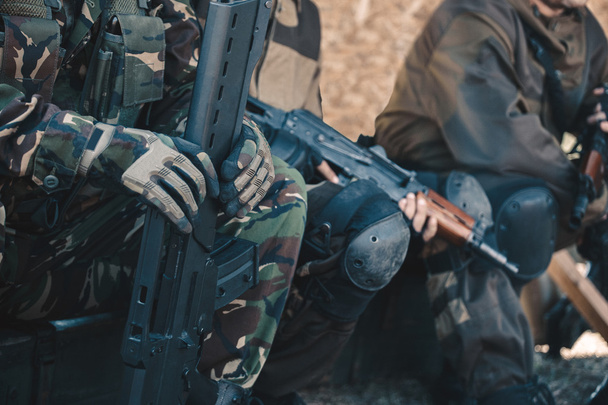 Zwei Soldaten in Tarnung und Handschuhen halten die Hände in den Maschinen. - Foto, Bild