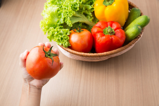 Tomate à portée de main avec légumes frais préparés dans un bol sur t en bois
 - Photo, image