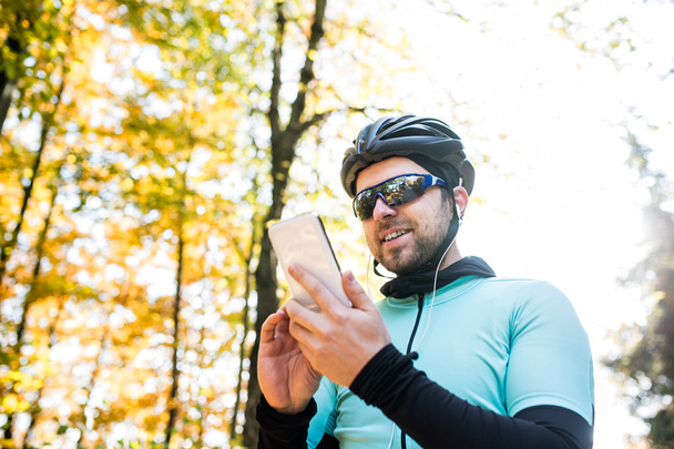 sportsman riding bicycle, holding smartphone  - Foto, imagen