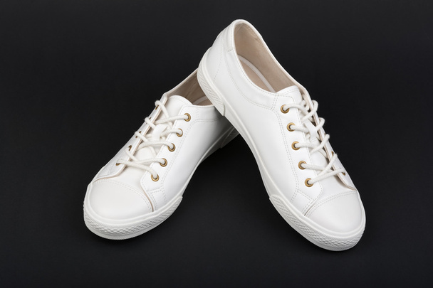 Λευκά αθλητικά παπούτσια των γυναικών σε σκούρο φόντο - Φωτογραφία, εικόνα
