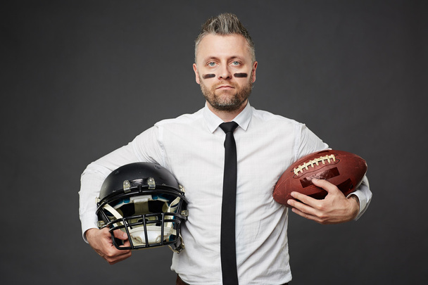 Man holding rugby ball and helmet - Foto, imagen