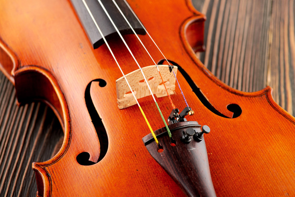 Крупним планом деталь скрипки на дерев'яному столі
 - Фото, зображення