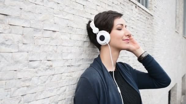 woman leaning against wall, listening music  - Footage, Video