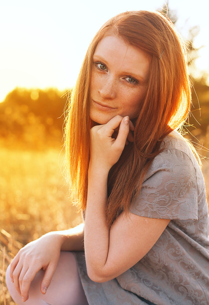 Молодая красавица с рыжими волосами на золотом поле на закате
. - Фото, изображение