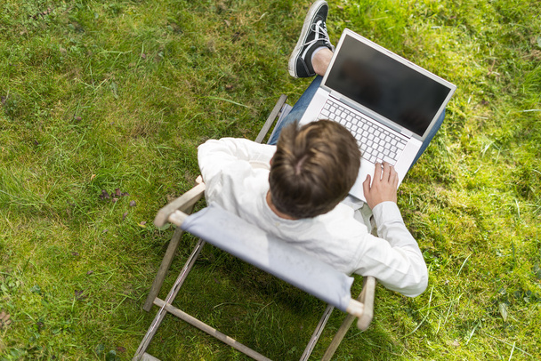 Lintu näkymä mies kirjoittamalla hänen kannettava tietokone ulkona
 - Valokuva, kuva