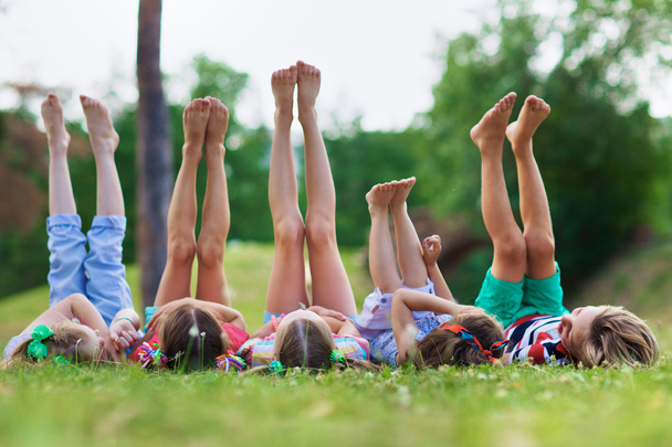 Vriendelijke kinderen met verhoogde benen  - Foto, afbeelding