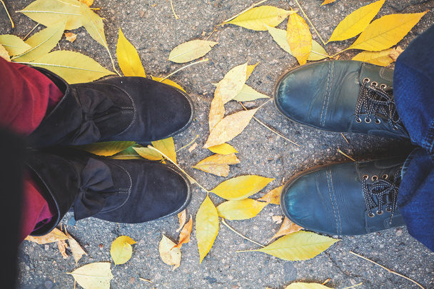 Autumn romance. Legs of man and woman on fallen leaves - Foto, imagen