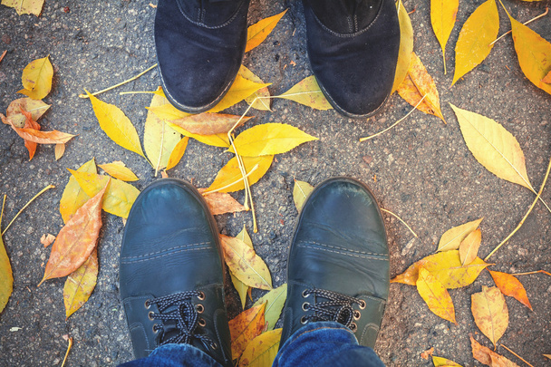 Autumn romance. Legs of man and woman on fallen leaves - Foto, imagen