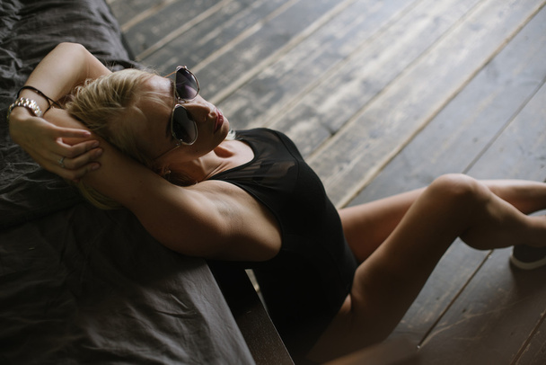 Yatağın yanında poz ve ellerini başının arkasına tutan kadın - Fotoğraf, Görsel