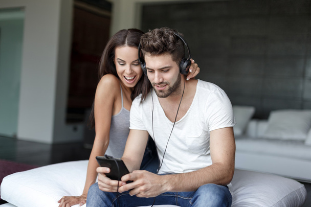 Rento valkoihoinen pari kuuntelee musiikkia tabletilla
 - Valokuva, kuva