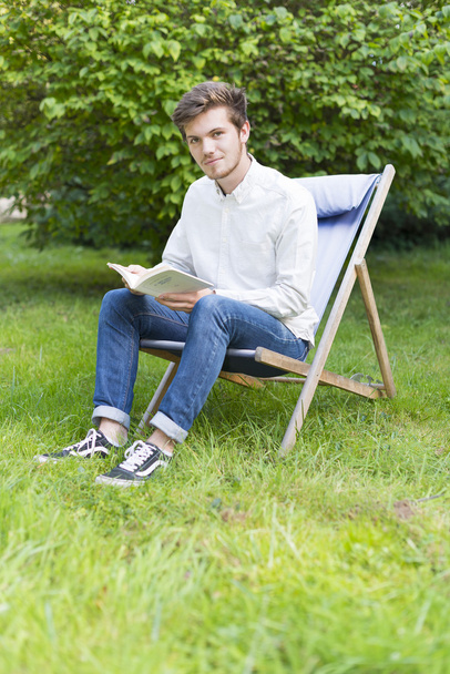 Sentado joven barbudo en el jardín mirando a la cámara
 - Foto, Imagen