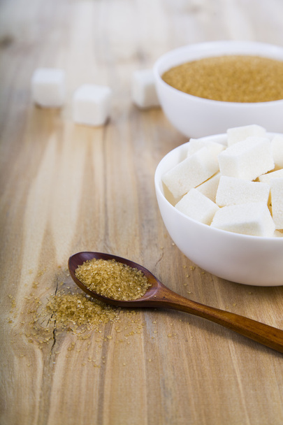 Ζάχαρη από ζαχαροκάλαμο και το λευκό σε ένα λευκό κύπελλα   - Φωτογραφία, εικόνα