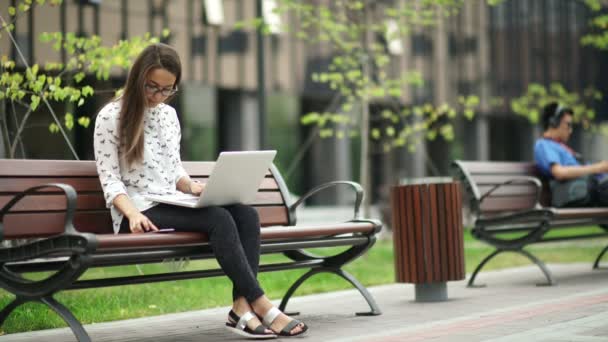 Beautiful girl with a laptop sitting on the street. - Metraje, vídeo