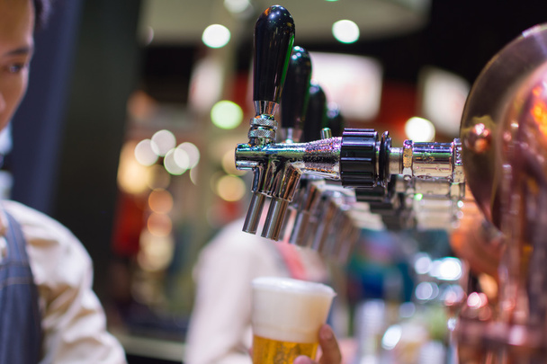 Бармен или бармен наливают пиво из пивного крана
 - Фото, изображение