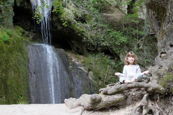 Little girl meditate by the waterfall - Photo, Image
