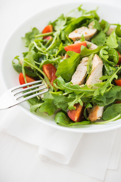 frischer Salat mit Huhn, Tomate und Gemüse (Spinat, Rucola) auf weißem Hintergrund in Großaufnahme. gesunde Ernährung. - Foto, Bild