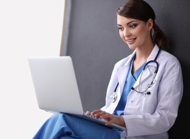 Médica mulher sentada e trabalhando em um laptop - Foto, Imagem