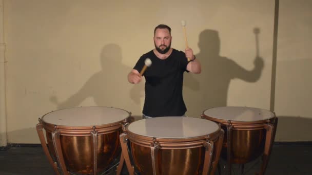 One Man With a Beard in Black T-Shirt, Playing on the Percussion Instrument Timpani (en inglés). sobre el fondo de las paredes brillantes
. - Metraje, vídeo