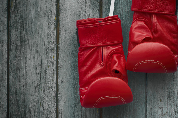 pair of red boxing gloves on an old shabby  wooden wall - Photo, Image