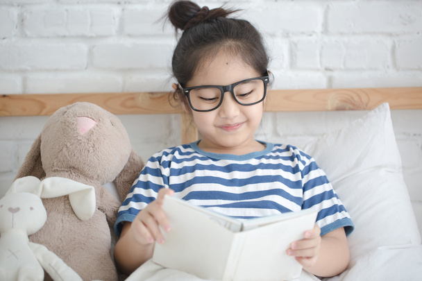 Gelukkig Aziatisch meisje lezen verhaal boek op het bed - Foto, afbeelding