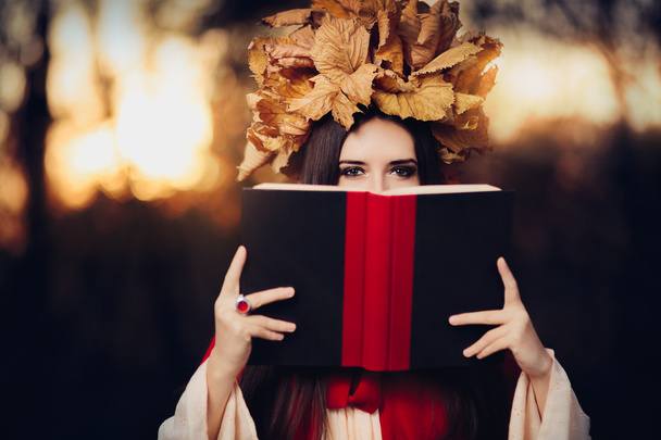 Frau mit Herbstlaubkrone liest ein Buch - Foto, Bild