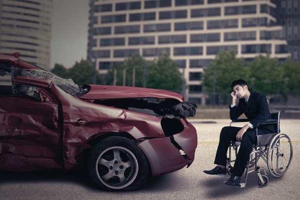 Gehandicapte persoon met beschadigde auto ziet er triest - Foto, afbeelding