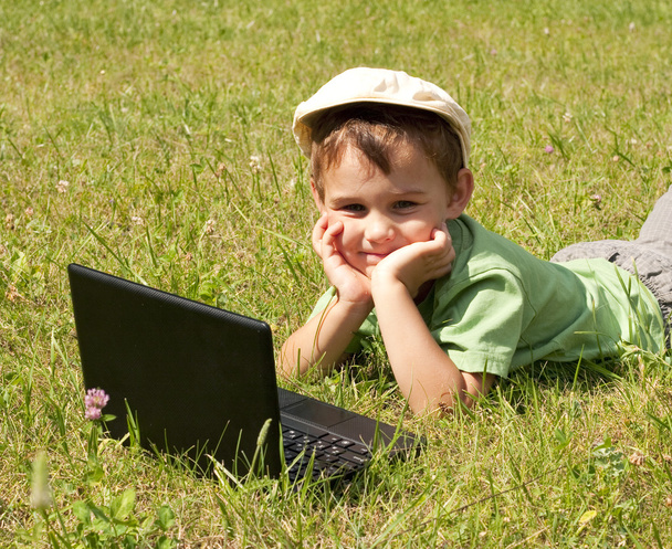 Kid with laptop on green meadow - Valokuva, kuva