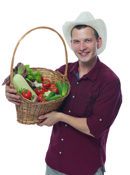 farmer in a red shirt holding a basket of vegetables - Fotó, kép