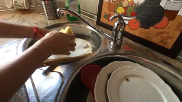 Femme d'âge moyen lave la vaisselle dans l'évier de la cuisine
 - Séquence, vidéo