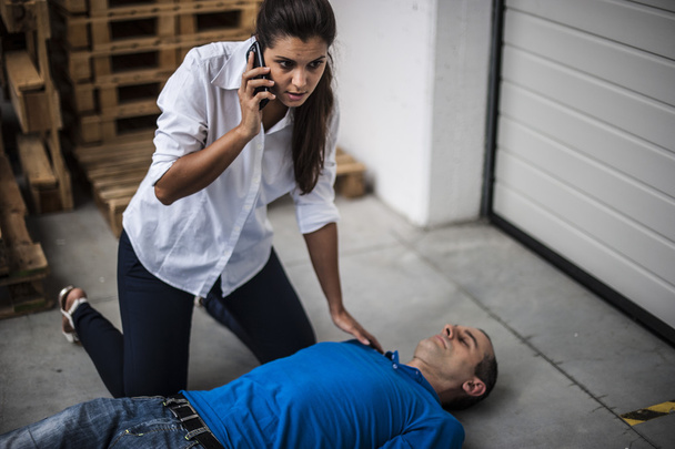 Menina chamando o serviço de emergência para um cara inconsciente
 - Foto, Imagem